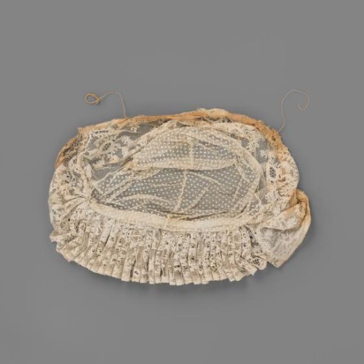Tulle cap with Roeselare lace; the crown of tulle embroidered with puffwork is edged along the forehead with a pleated strip of Roeselare lace