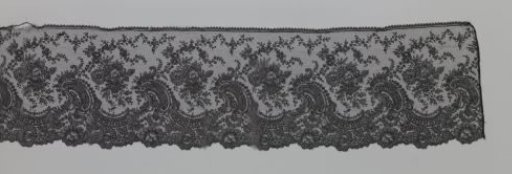 Japanese strip of black bobbin lace with waves of C-scrolls and flower clusters