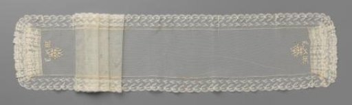 Bow tie of machine-made tulle with embroidered letters M J and a small bouquet, surrounded by a border of machine-made lace with stylised branches with knot and leaf