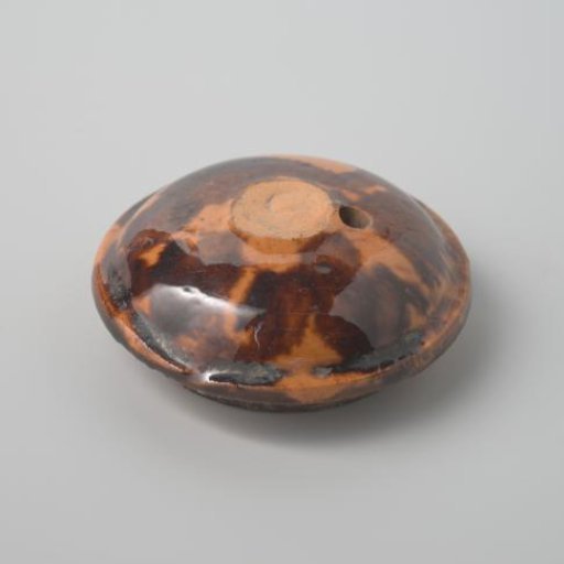 Lid of earthenware with brown spots and a yellow glaze (De Caluwe kiln waste)