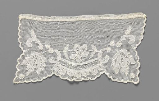 Cuff of lace embroidery with a symmetrical pattern of a rose above a decorative band with a zigzag and godrons