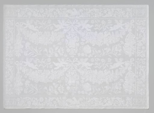 Napkin of white linen damask with a pattern of putti with festoons and monograms in the corners