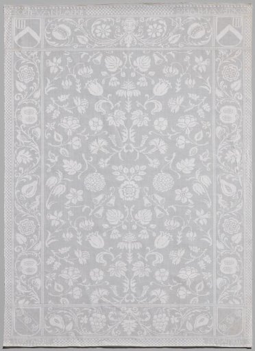 Tablecloth of white linen with pattern of scattered flowers with woven coats of arms and names ZOETE VAN LAEKE and HERTAING.