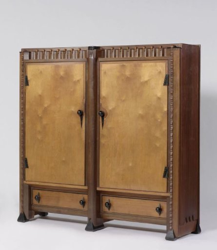 Cabinet with two doors and drawers below with an intricately carved ornament