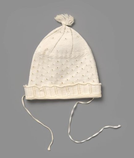 Knitted cap of white cotton with openwork circles, a turned-down border and a tassel on top, with radiating openwork borders around
