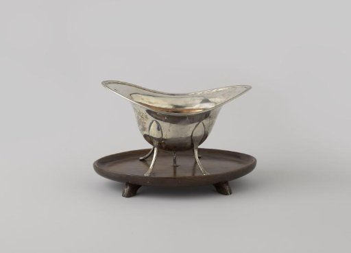 Pipe warmer of silver on a mahogany top and with an inner bowl of red copper. Arched and slightly rising on both sides. Four curved legs.