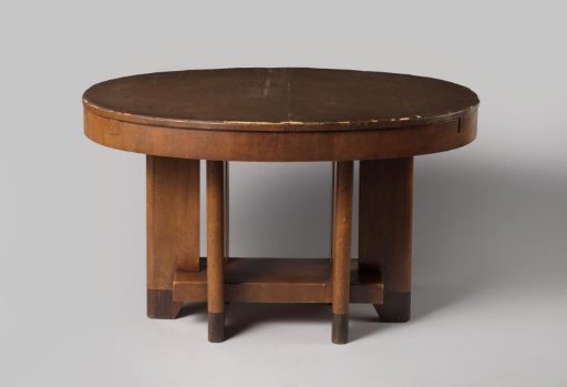 Table, oval, extendable, on six broad flat legs, connected by a rectangular plateau. The table includes two extendable leaves