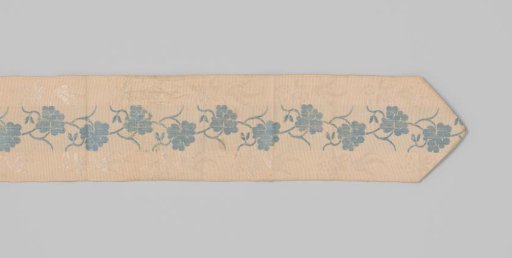 Belt ribbon of cream-colored silk in taffeta weave, decorated with brocaded work; running across the middle of the ribbon is a leafy vine in blue, flanked on both sides by berry branches in white