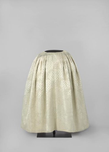 Skirt with side slits and grey glazed lining of quilted and stitched white satin with diamonds and leaf vines and abstract floral and leaf motifs full of stripes and pips