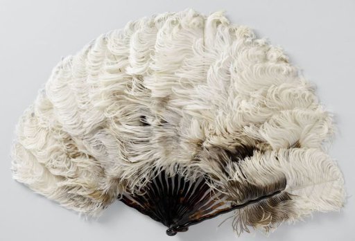 Folding fan of whitish-brown ostrich feathers on a mount of narrow, twisted legs of plastic with tortoiseshell pattern