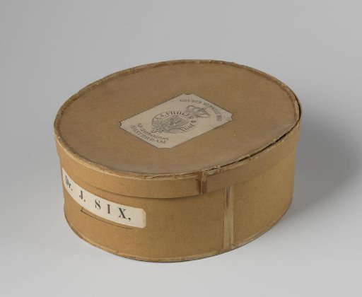 Oval box of brown cardboard, with a label on the upright side reading "Dr. J. Six" and on the lid a label reading "Amsterdam, J.J. Froger & Zoon"