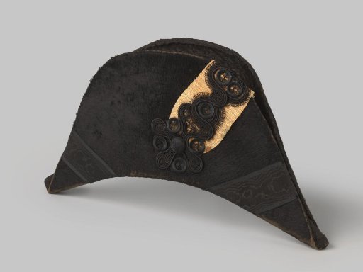 Flat foldable mourning cap of black silk velvet, decorated with a black flower over a pale-orange pleated cockade and black moiré ribbons