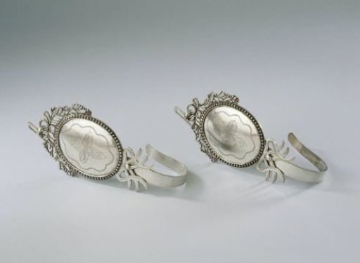 Silver mosquito net hook. The hook is attached to an oval shield with an engraved decoration of a stylized leaf motif