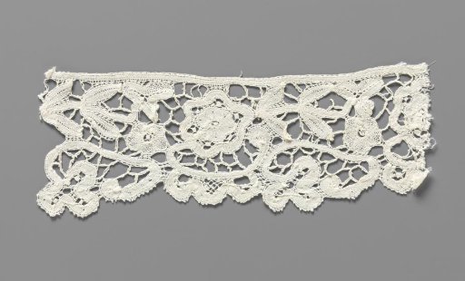 Cuff of a strip of bobbin lace with a rosette flower on a C-shaped stem with three lobes hanging below