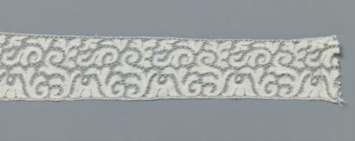 Strip of machine-made lace with hanging cup flower between loose S-scrolls