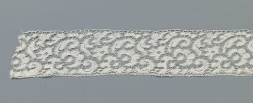 Strip of machine-made lace with irregular five-pointed flower on center line between loose leaves and flowers