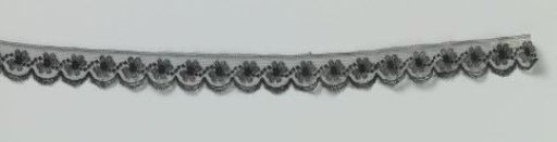 Strip of black machine lace with wavy dotted line between daisies