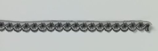Strip of black machine-made lace with wavy dotted line between daisies