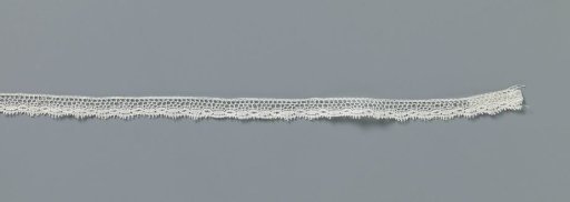 Strip of machine-made lace with a series of alternating closed and openwork ovals along the lower edge