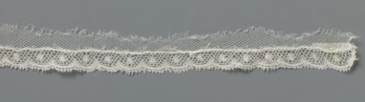 Strip of bobbin lace with a dot in a shell