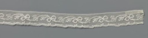 Strip of bobbin lace with bow and rosette flower in a wavy vine