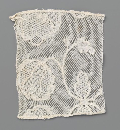 Strip of bobbin lace with a part of two facing round flowers with a bow