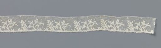 Strip of bobbin lace with a branch of starflowers and a thick branch with side branches