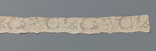 Strip of bobbin lace with flower branches between horn-shaped reserves