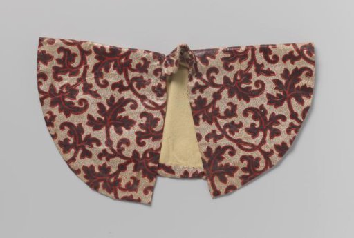 Children's jacket of chintz with a white ground with blue leaves edged in red, with a round neck, V-shaped yoke, pleated front panel and long sleeves