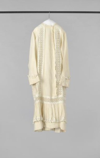 Child's dress with long sleeves, straight at the back, at the front with very low waist, fastening, pleated skirt and two patch pockets, of ecru linen, decorated with English embroidery