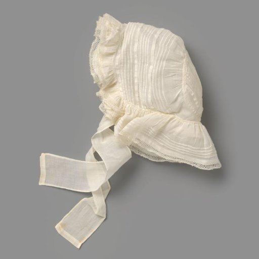 Girl's cap of thin white cotton, entirely decorated with smocking, with wide ribbon bows of the fabric; in front three frills with lace edging