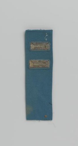 Cuff of blue cloth with two appliqués of silver embroidery