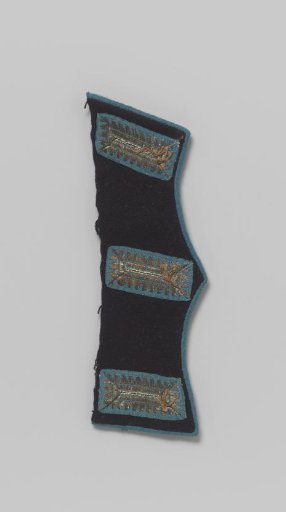 Pocket flap of dark blue cloth with three blind buttonholes around which is embroidered with silver thread