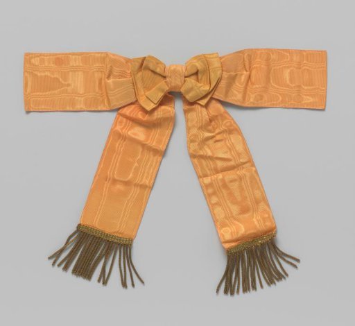 Shoulder knot of orange moiré ribbon with fringe of gold thread