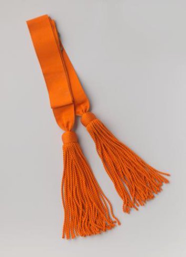 Sash of orange ribbed silk, with two silvered buckles and tassels of thick and long cord, with a head in the shape of a half-sphere; housed in a small box (b)