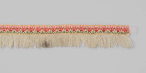 Passementerie of woven white wool, unpicked on one of the long sides to create a fringe; the wool is decorated along the length with embroidered flowers