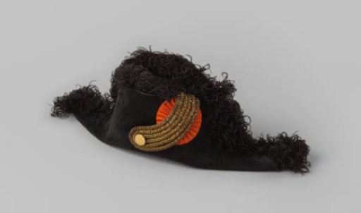 Cut of black felt, decorated with black ostrich feathers, gold-colored lis and orange cockade