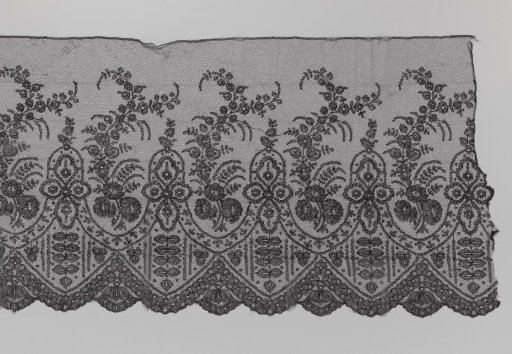 Strip of black bobbin lace with wavy upright branches