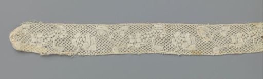 Strip of bobbin lace with loose floral scrolls with reserve