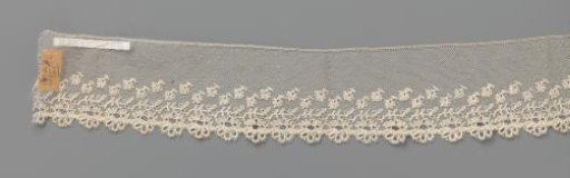 Strip of bobbin lace with daisies with open flower centers