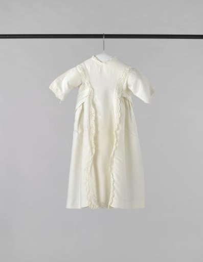 Dress for a child of white cotton piqué with transverse ribbing and decorated with strips of English embroidery.