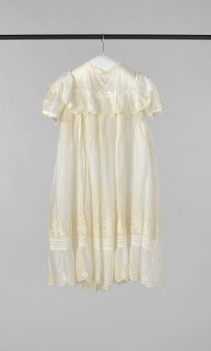 Children's dress with short puffed sleeves and back fastening of white cotton decorated with English embroidery, smocking and along the neck with a lace edge.