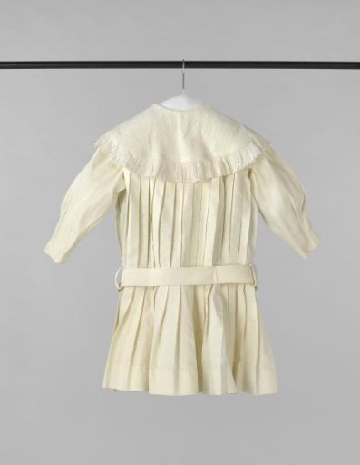 A toddler's dress of pleated piqué, with a round flat collar with batiste ruffles and a fabric belt