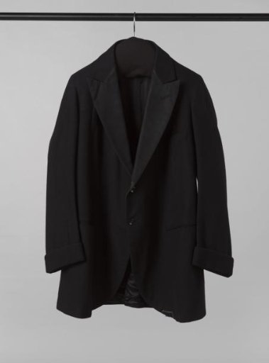 Smoking jacket of black cloth, with rounded front panels, lapels with black satin, closure with two black buttoned legs, three slash pockets and long sleeves with turn-ups