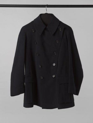 Short jacket with wide lapel, fastening with double row of black horn buttons and two sewn-on pockets with box pleat and flap of black cloth, lined with black satinette
