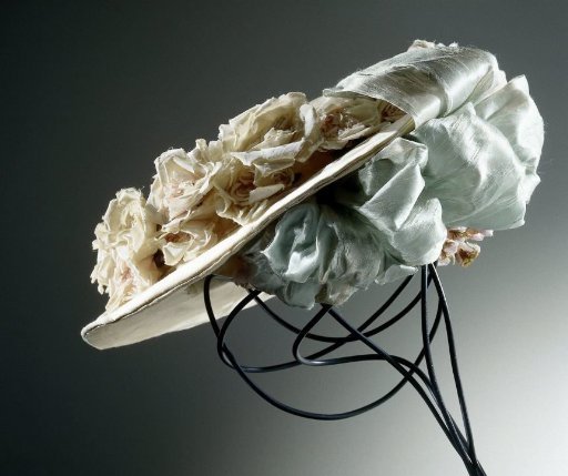 Hat of white satin decorated with rose flowers and light blue ribbons, somewhat oval, flat model