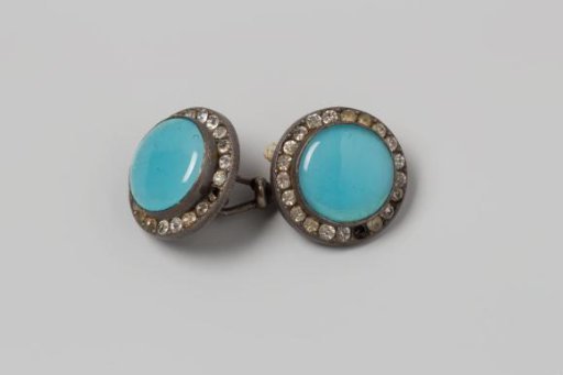 Cufflink consisting of a light blue round stone with a setting of rhinestones