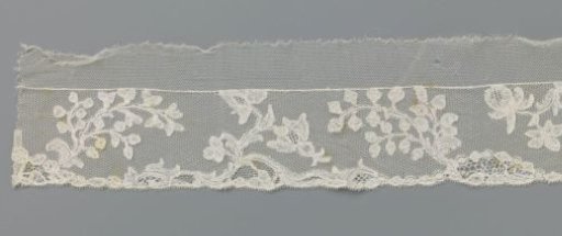 Strip of bobbin lace with curved branches and pomegranates