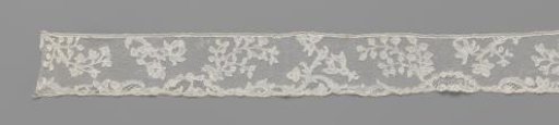 Strip of bobbin lace with curved branches and pomegranates
