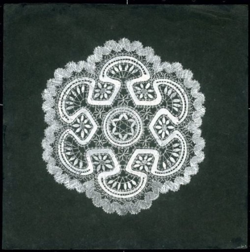 Lace design of a carpet in hexagonal shape, in white ink on black card